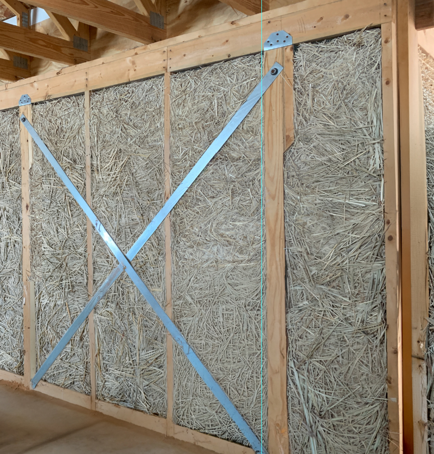 Light straw clay infill packed between studs in a conventional 2×6 wood frame.
